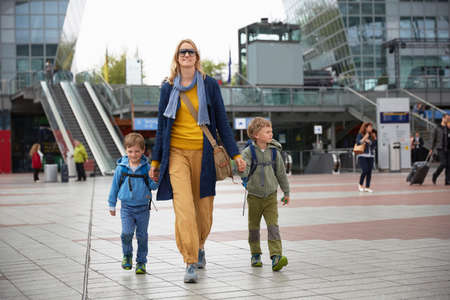 Front view of mother and sons at airport holding handsの写真素材