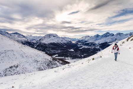 Man walking on snow covered mountain, rear view, Engadine, Switzerlandの写真素材