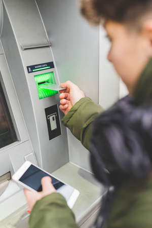 Young woman using cash machine, rear viewの写真素材