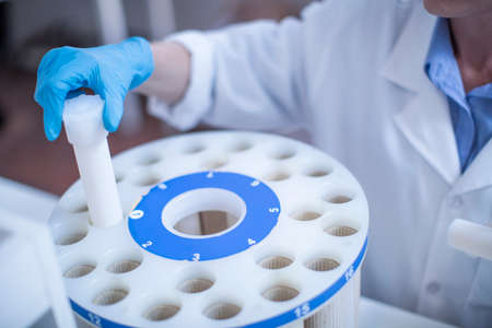 Mid adult woman in laboratory inserting test tube into trayの写真素材