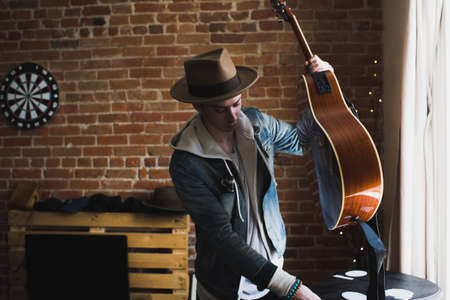 Young man at home, holding guitar, ready to playの写真素材