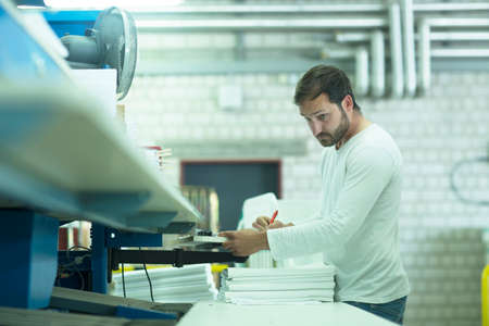Man working in launderette making notesの写真素材