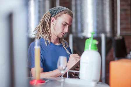 Man in microbrewery quality checking craft beer