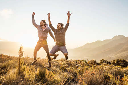 Friends on grassland, arms raised jumping