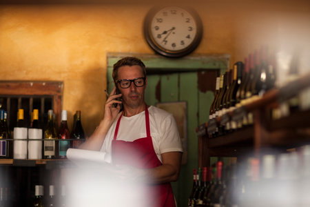 Man working in wine shop making telephone callの写真素材