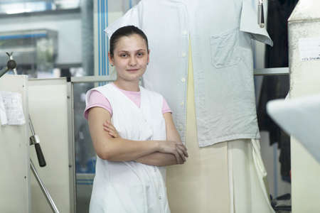 Woman in launderette in front of steaming dummyの写真素材
