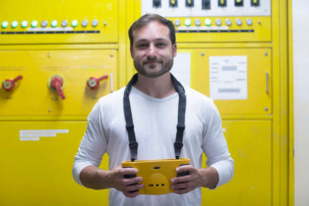 Man in front of yellow control panel smilingの写真素材
