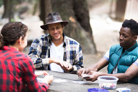 Three young adult hikers playing cards in forest, Arcadia, California, USAの写真素材