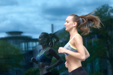 Young woman training, running past office windowの写真素材