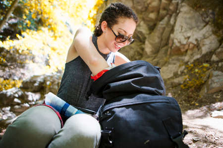 Young female hiker sitting on rock searching rucksack in forest, Arcadia, California, USAの写真素材