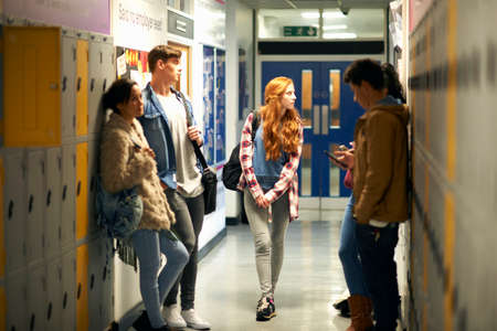 Five young adult students waiting in college locker roomの写真素材