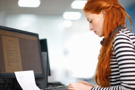 Young female college student typing at computer desk