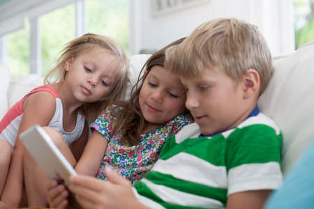 Siblings on sofa using digital tabletの写真素材