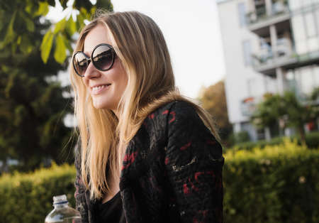 Young woman sitting outdoors, holding water bottleの写真素材