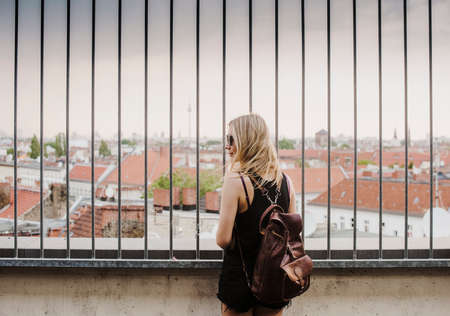 Young woman looking through railings, at view across rooftops, rear viewの写真素材
