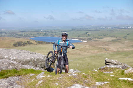 Cyclist carrying bicycle on rocky outcrop