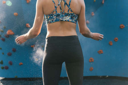 Young woman dusting hands, preparing to use climbing wall, mid section, Brooklyn Bridge Park,...