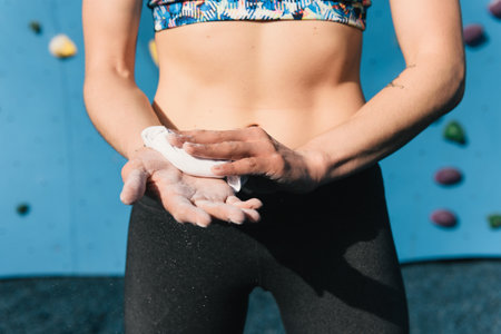Young woman dusting hands, preparing to use climbing wall, mid section, Brooklyn Bridge Park,...