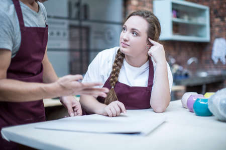 Male potter explaining ideas to trainee in workshop
