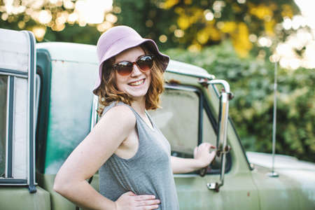 Woman wearing sunhat and sunglasses looking over shoulder at camera smiling