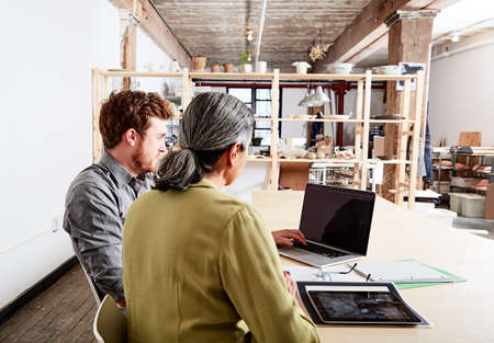 Colleagues at desk in workshop looking at laptop computer