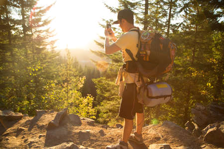 Male hiker taking smartphone photograph from forest ridge, Mount Hood National Forest, Oregon, USA