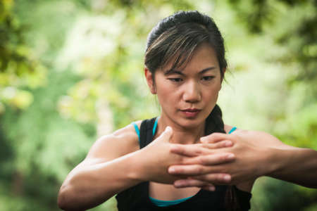 Mid adult woman exercising in forest, stretchingの写真素材