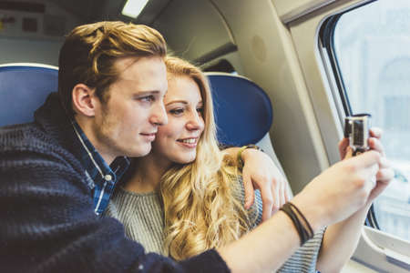 Young couple photographing through train carriage window, Italyの写真素材