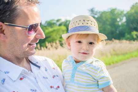 Father holding baby boy wearing straw hatの写真素材