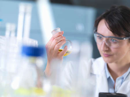 Scientist viewing chemical formula in beaker during  experiment in laboratoryの写真素材