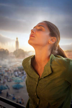 Woman in front of Jemaa el-Fnaa Square, head back, eyes closed, Marrakesh, Moroccoの写真素材