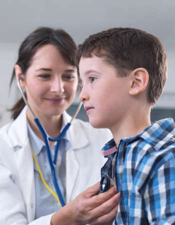 Doctor checking boy's breathing with stethoscope
