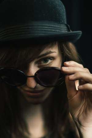 Portrait of woman looking over sunglasses at cameraの写真素材