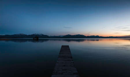 Wooden pier with view of mountains, at dusk, Rosenheim, Bavaria, Germanyの写真素材