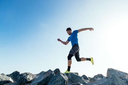 Man training, running on coast rocks, downtown San Diego, California, USAの写真素材