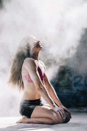 Powder covered woman kneeling smiling in cloud of dustの写真素材