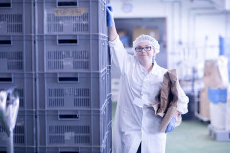 Factory worker holding packaging looking at camera smilingの写真素材