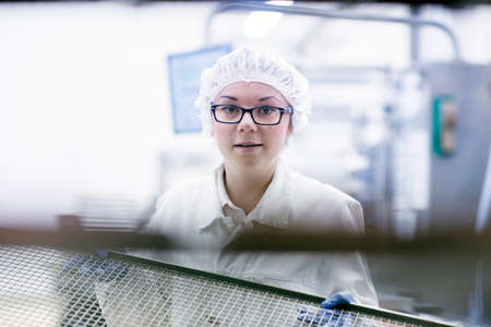 Factory worker wearing hair net looking at camera smiling