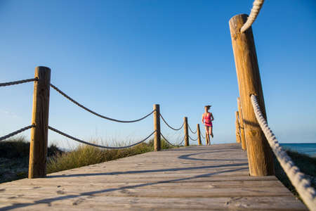 Young woman running  on wooden pathway, low angle viewの写真素材