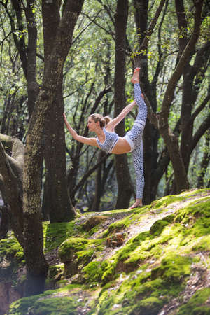 Woman on rock standing on one leg stretchingの写真素材