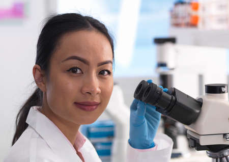 Scientist viewing a glass slide containing a sample for laboratory analysis