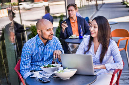 Business people sitting outside cafe, using laptopの写真素材