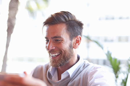 Mature man sitting outdoors, laughingの写真素材