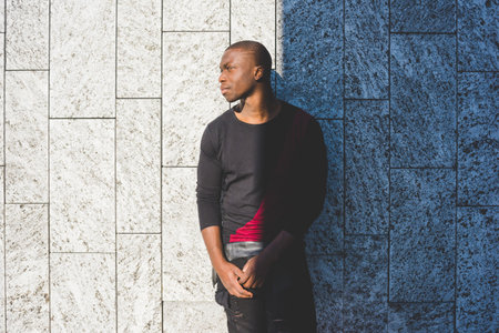Portrait of young man leaning against wall, looking awayの写真素材