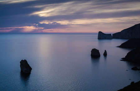 High angle silhouetted view of rock formations and cliffs at dusk, Masua, Italyの写真素材