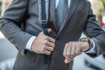 Neck down view of businessman checking wristwatch in cityの写真素材