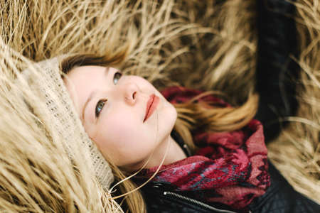 Woman lying in tall grass smilingの写真素材