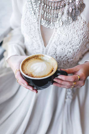 Cropped view of woman wearing white dress holding coffee cupの写真素材