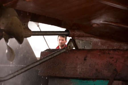 Male ship painter using pressure washer to clean ship hullの写真素材