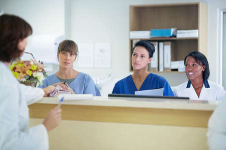 Female doctor having discussion with nurses at nurses station in hospitalの写真素材